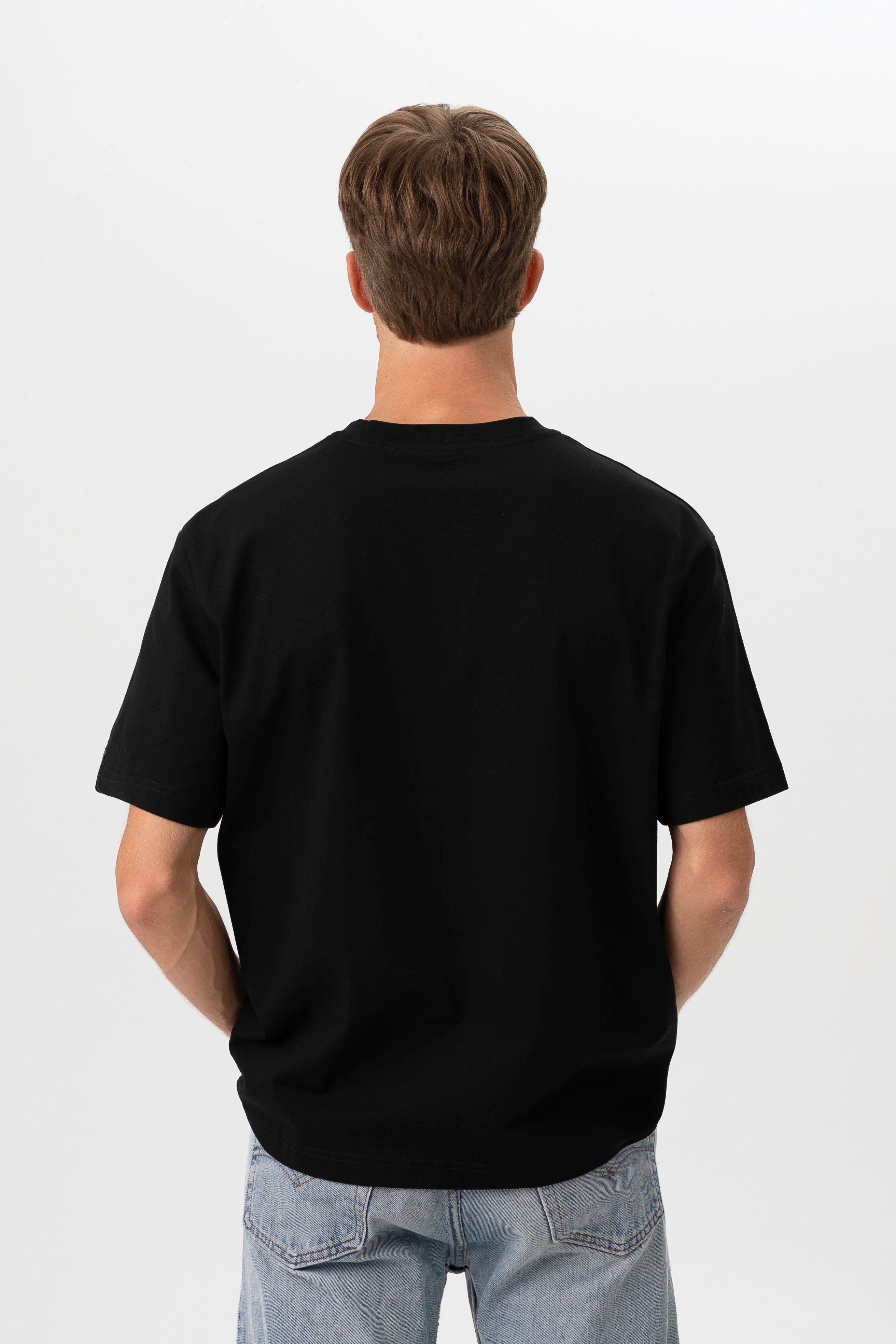 Vaizdas iš nugaros, demonstruojantis juodų oversized marškinėlių siluetą ir laisvą kritimą