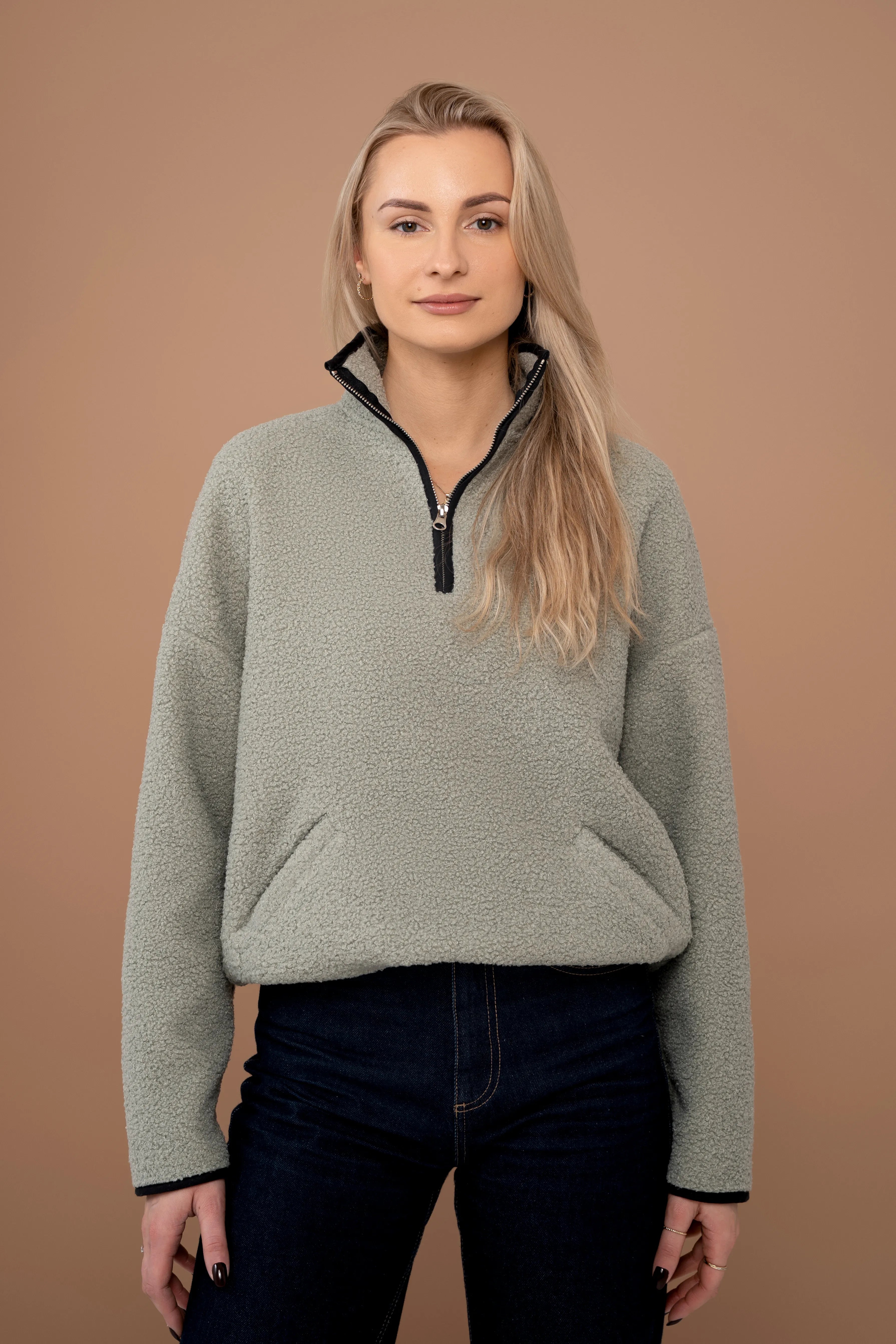 Women’s khaki jumper with a short zipper, stand-up collar, long sleeves, and a front view
