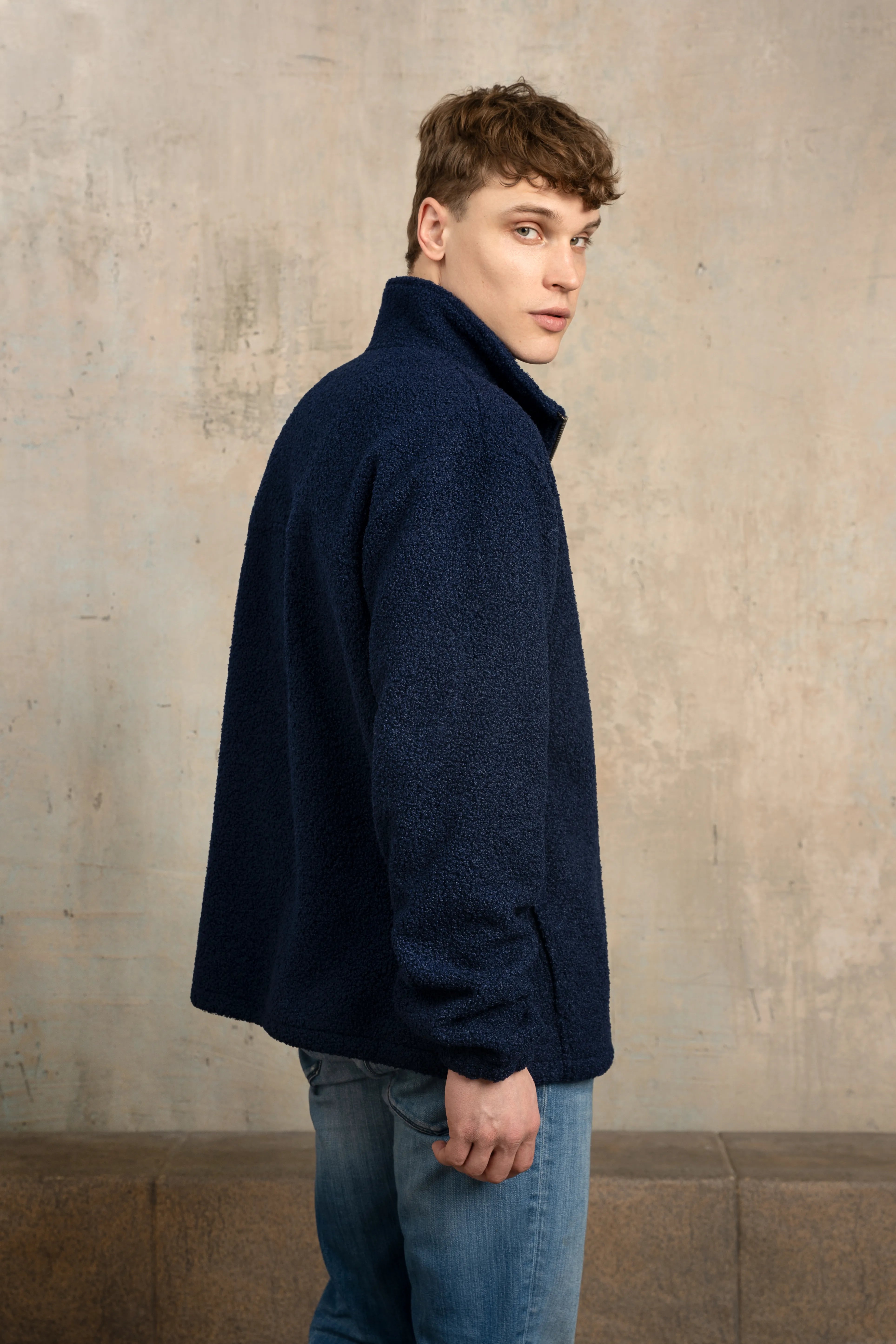 Dark navy men’s zip-up sweatshirt with a full-length zipper, stand-up collar, long sleeves, side view