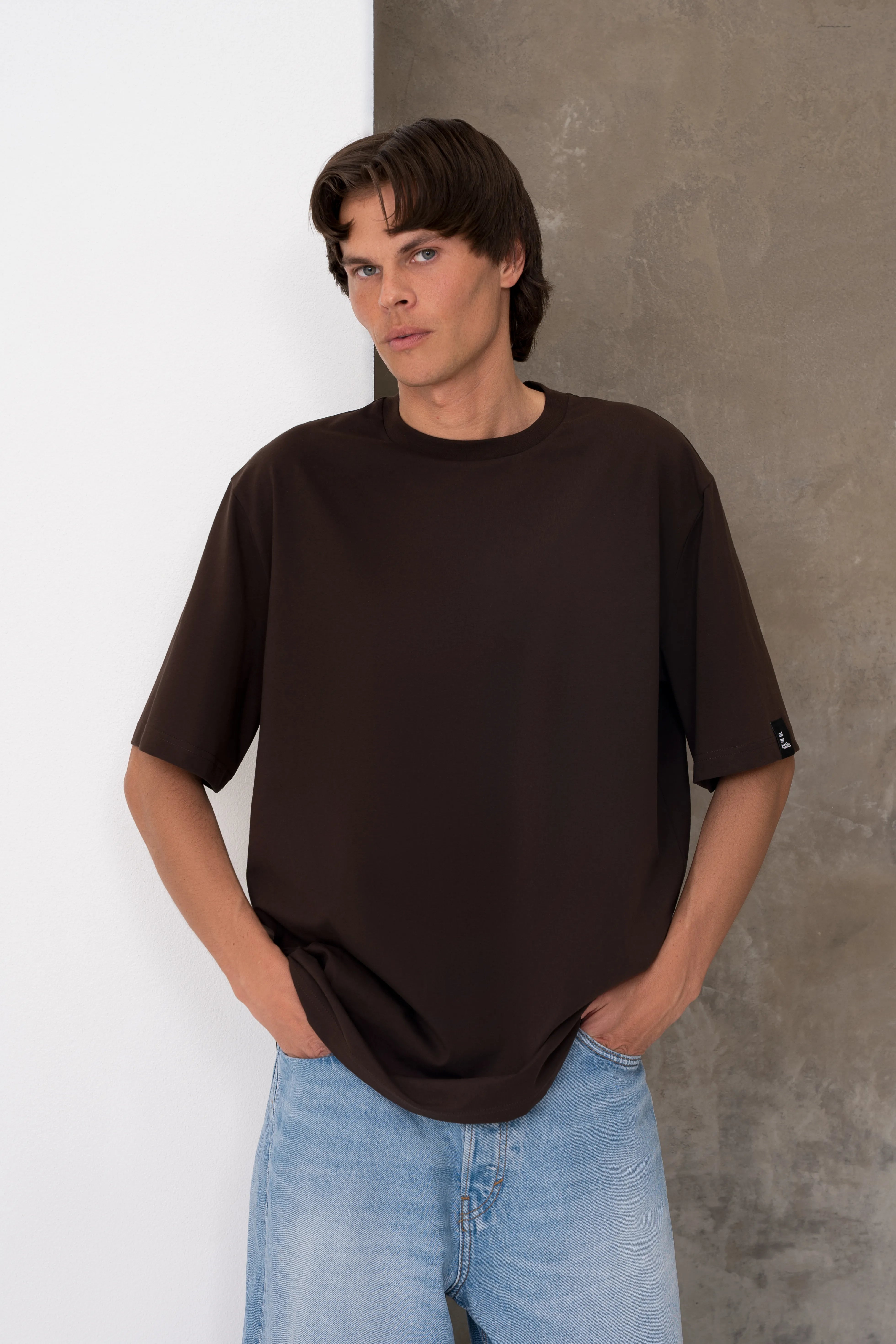 Rudi vyriški oversized marškinėliai trumpomis rankovėmis su apvalia kaklo iškirpte, nuleista pečių linija, laisvu siluetu ir juoda cutmyfashion etikete ant rankovės