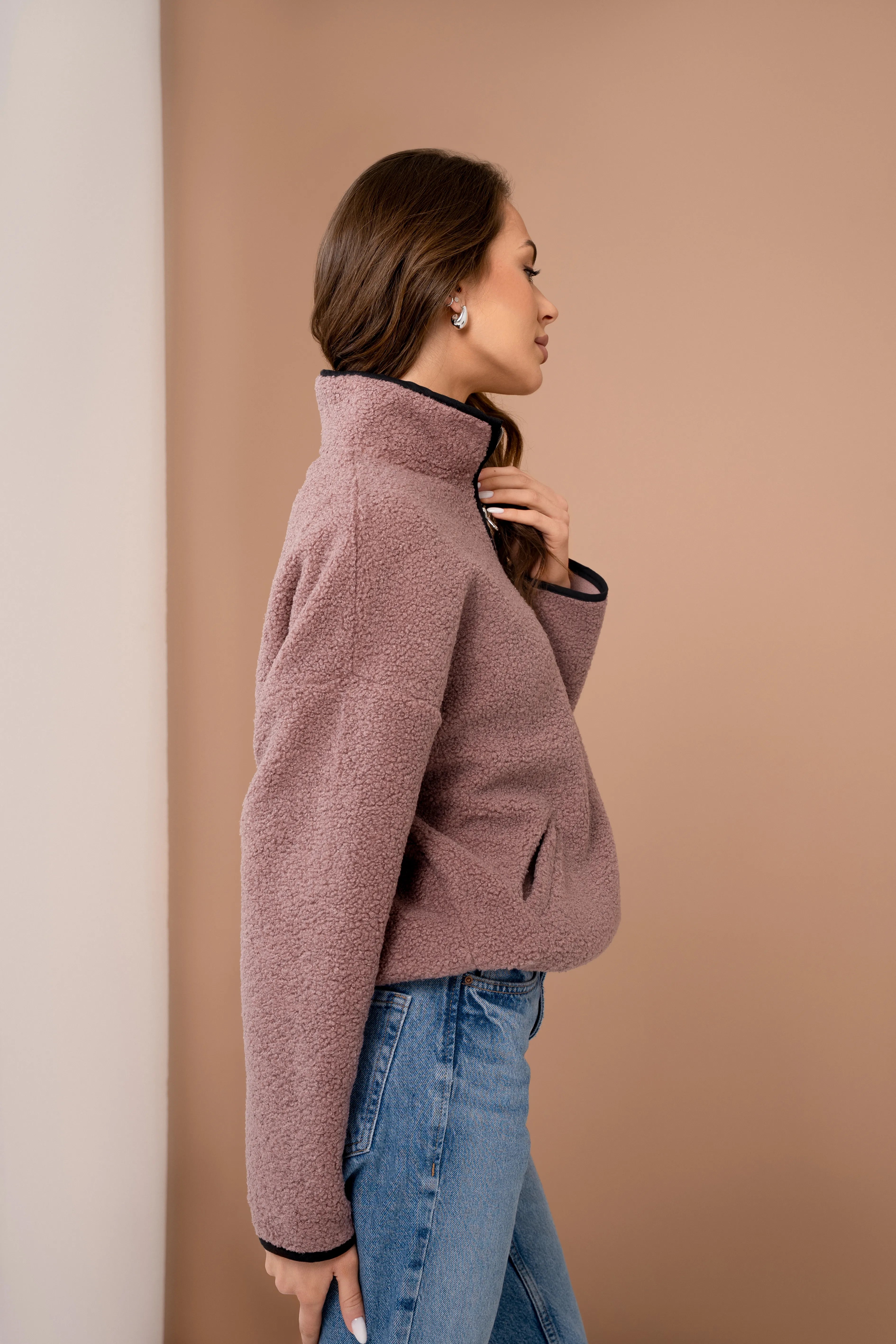 Pink women’s teddy sweatshirt with a short zipper, a stand-up collar, long sleeves, and a side view