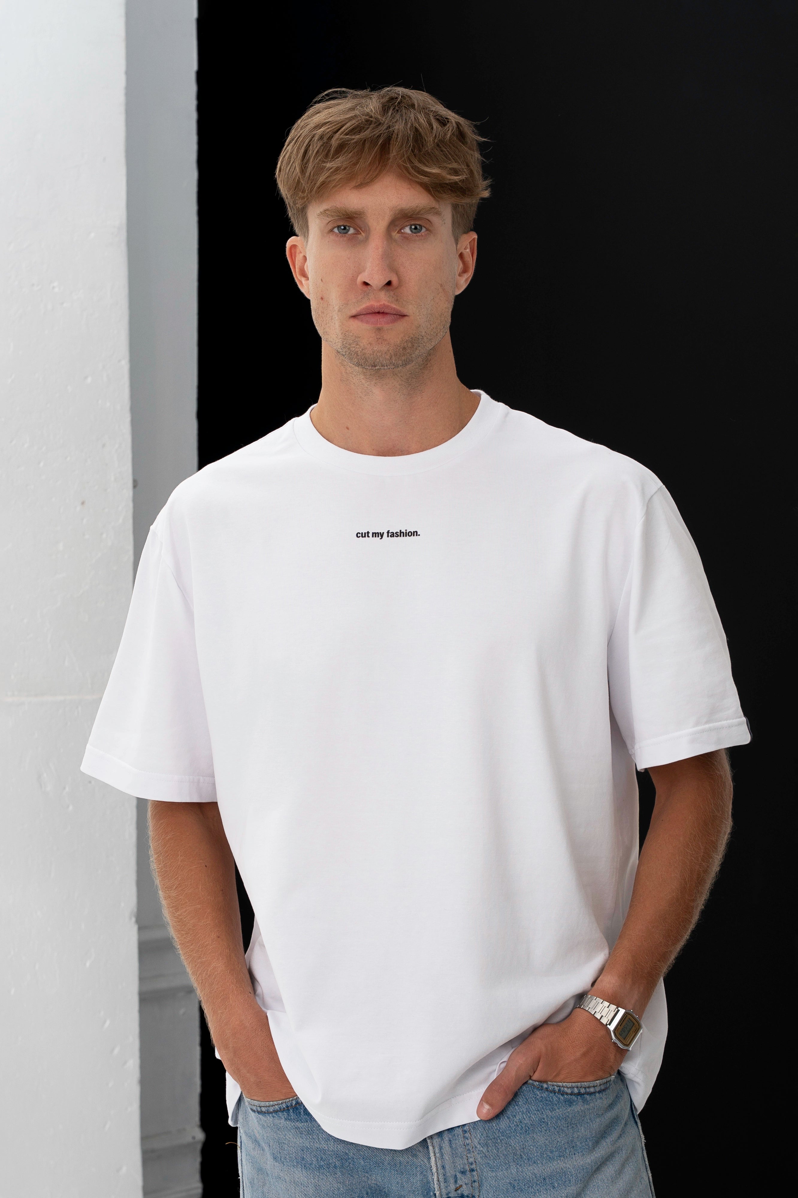 Vyras dėvi baltos spalvos cut my fashion oversized stiliaus marškinėlius, rankos sukištos į džinsų kišenes