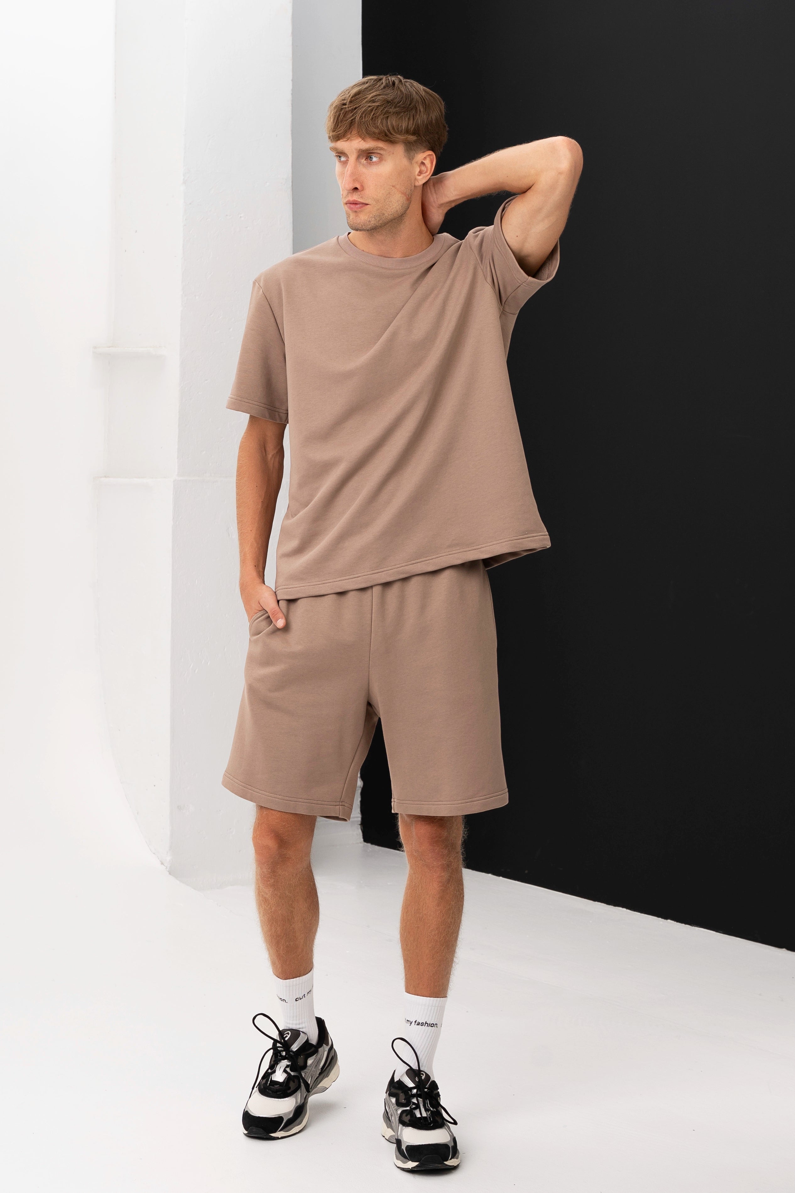 Side view of a man wearing a casual set with a T-shirt and shorts, looking into the distance
