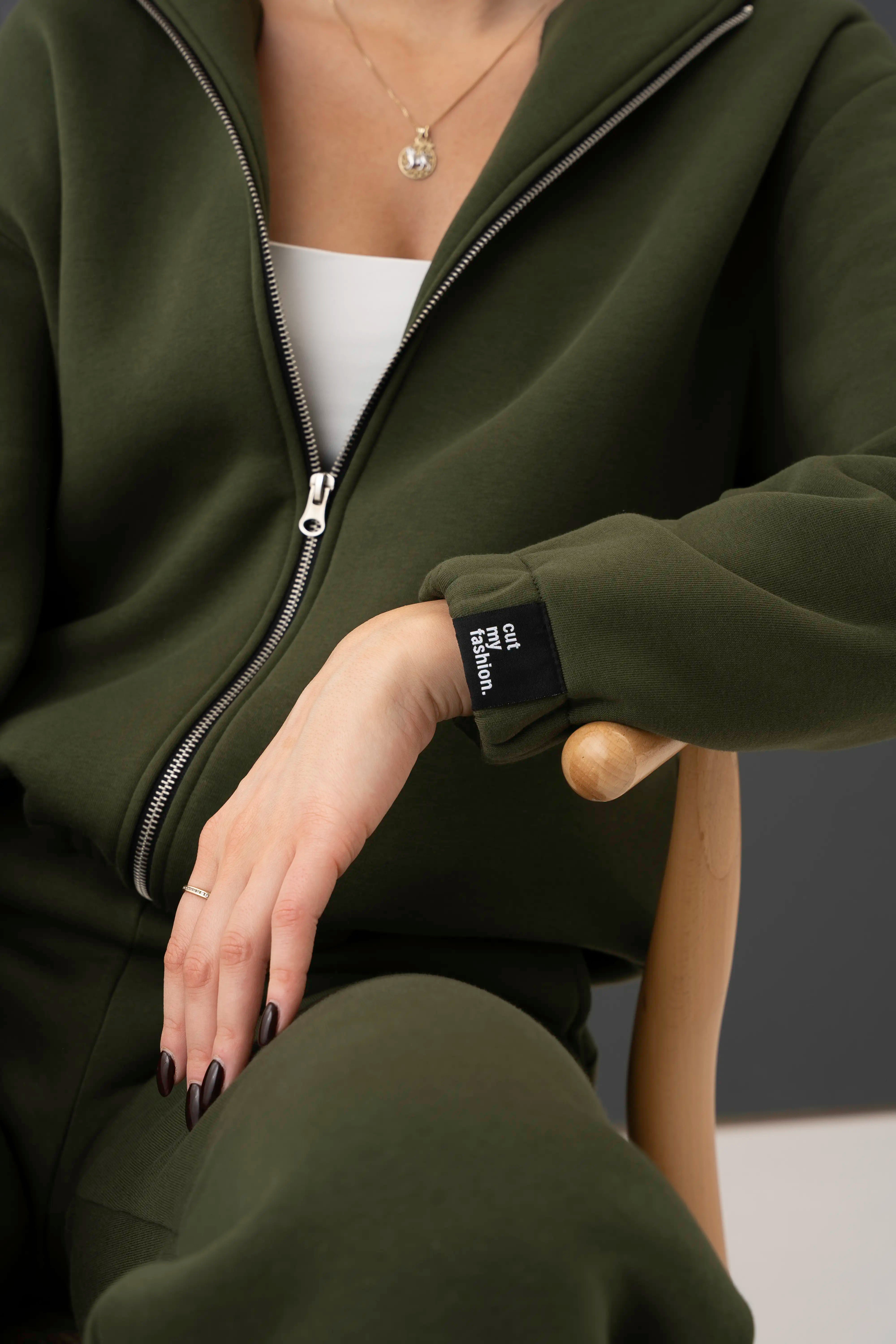 Chaki spalvos moteriško laisvalaikio treningo rankovė su guma, metaliniu pilno ilgio užtrauktuku ir rankovės etiketės detale