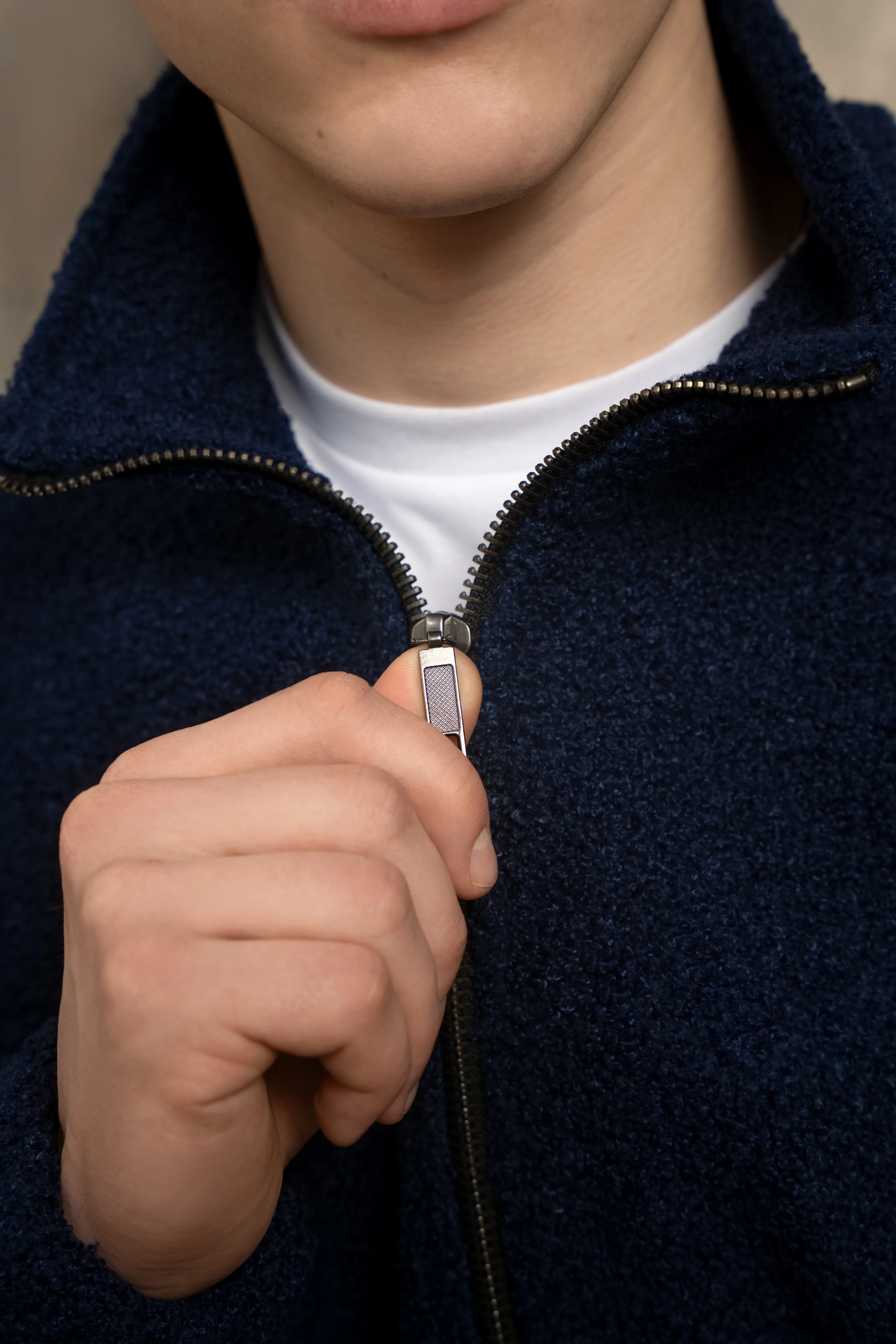 Detail of the metal full-length zipper and collar on the dark navy men’s sweatshirt