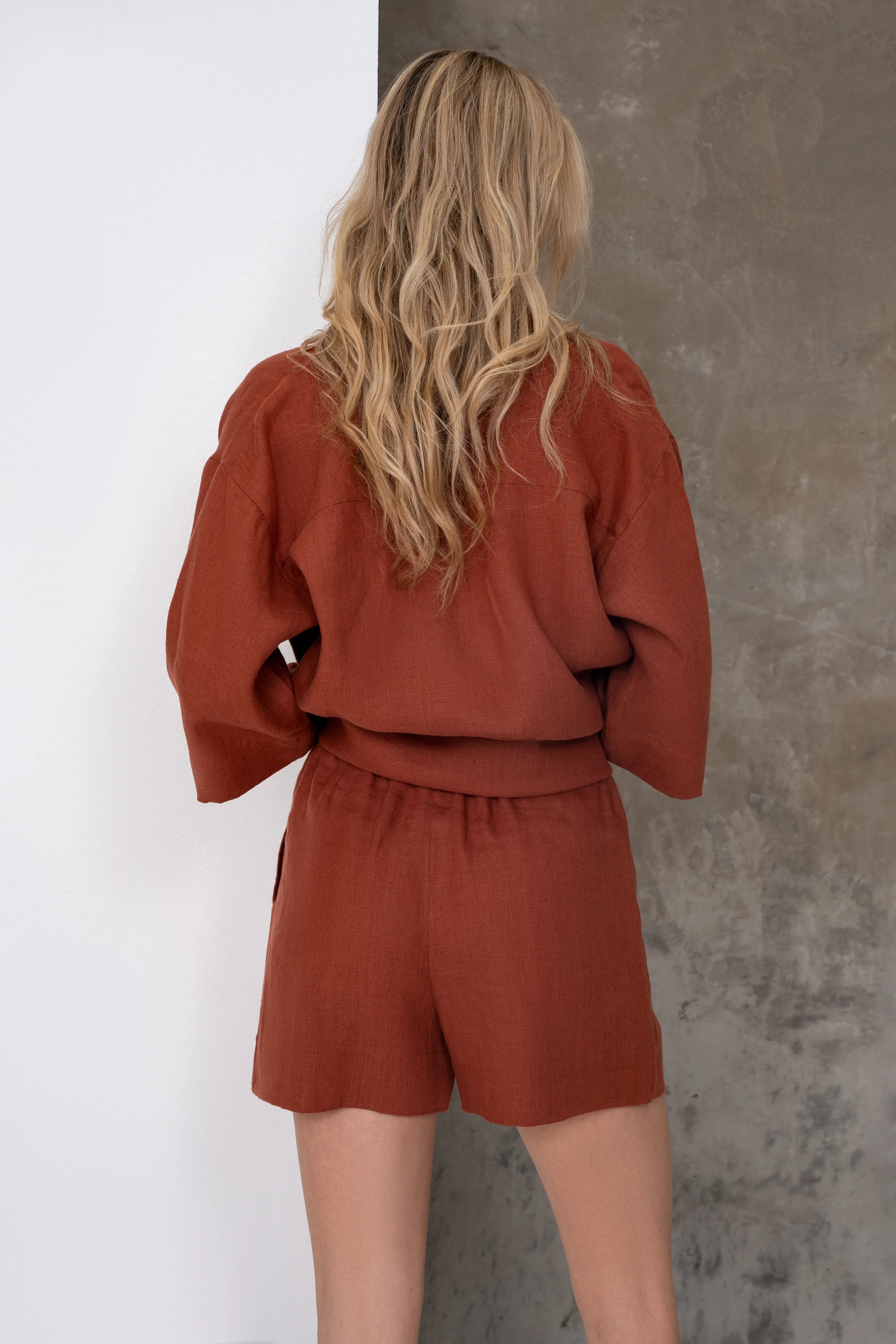 Brick-colored linen women's shorts, back view with a relaxed-fit shirt