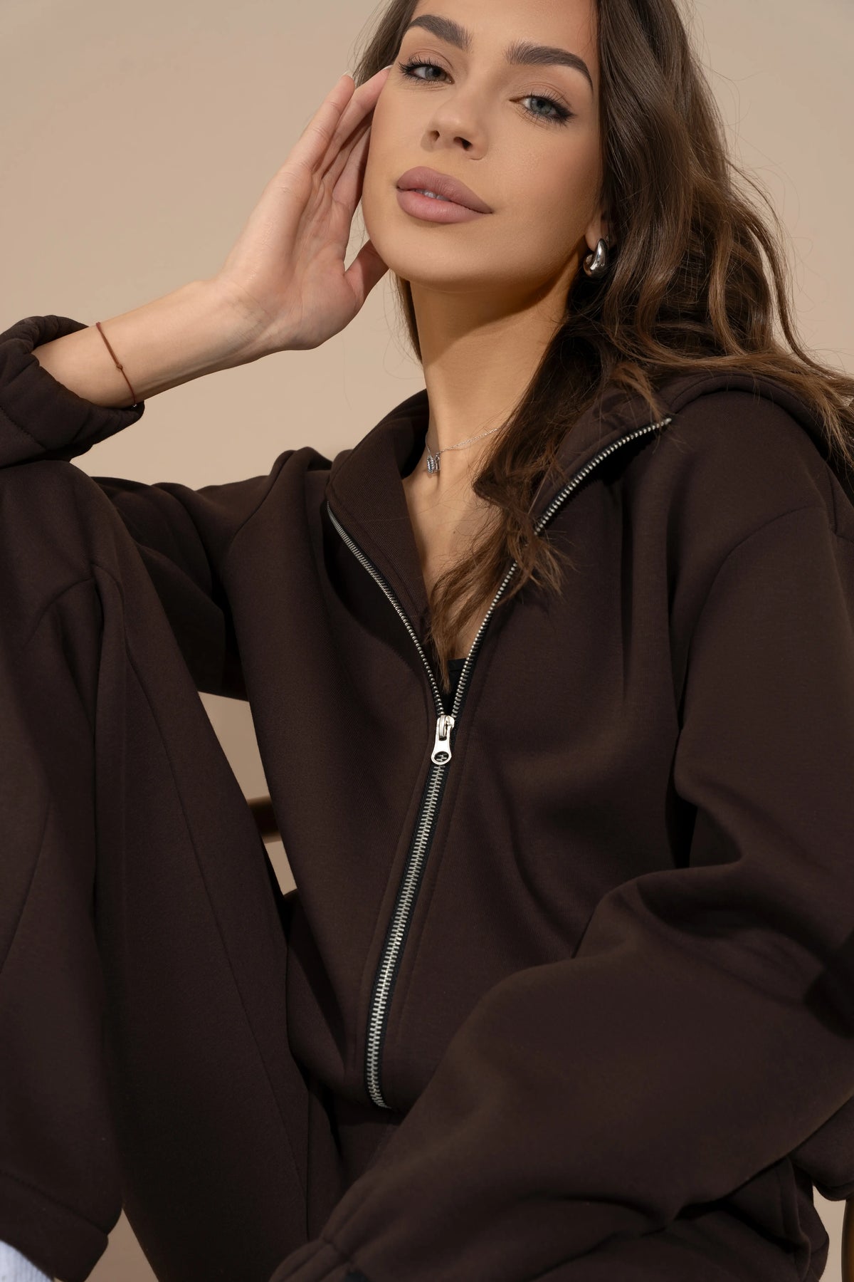 Detail of the full-length metal zipper and collar on a brown women’s hooded sweatshirt