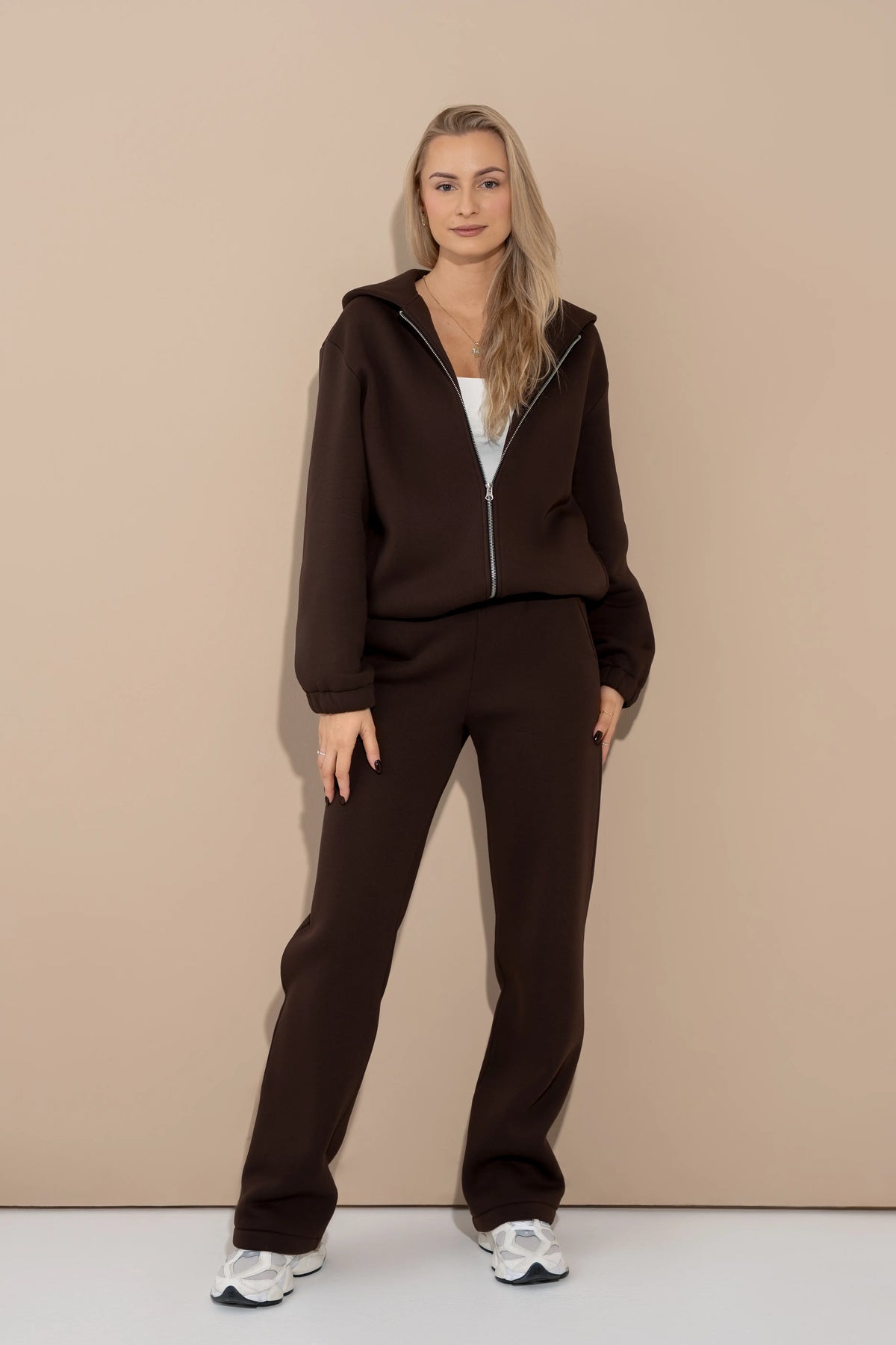 Brown women’s casual tracksuit with a hood, a full-length metal zipper, and straight casual trousers